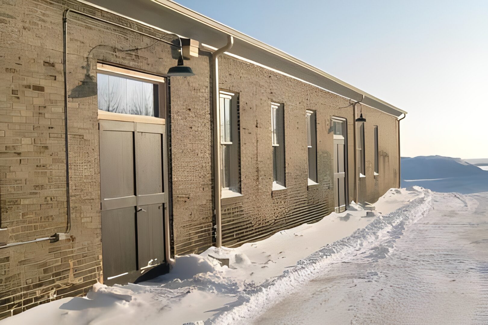 Brick building with snow-covered ground and path.